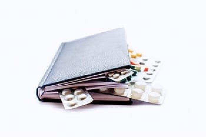 medical book with pills as a bookmark between the pages, Isolated on white background